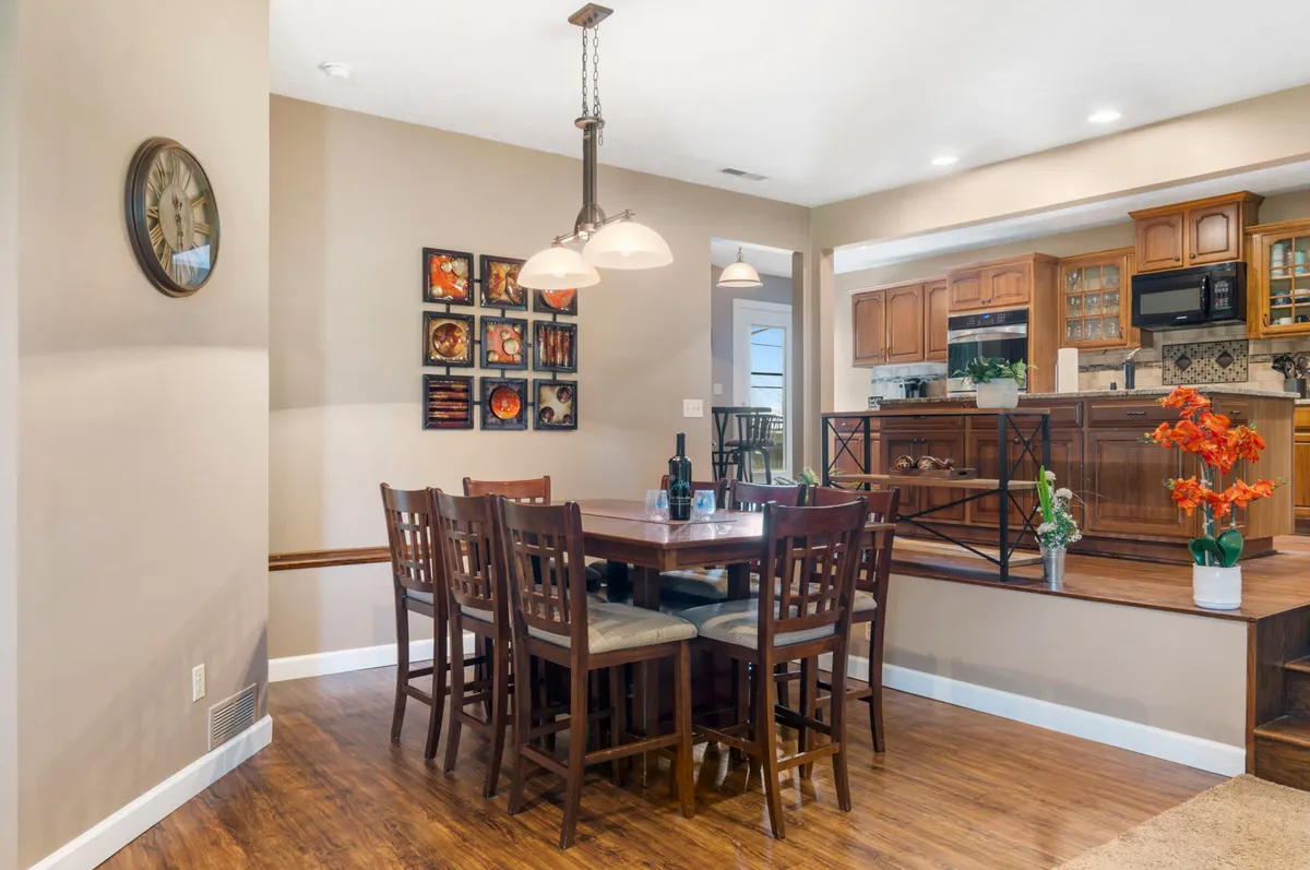 A spacious dining area with a long table, decorative wall art, and a kitchen area in the background. The room exudes warmth and is set up for family meals, celebrations, and communal gatherings.