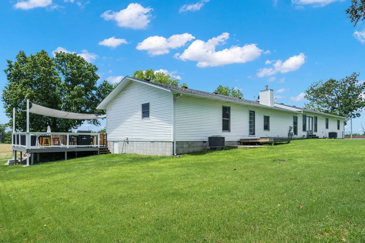 An inviting view of the house’s exterior highlights the deck area, lush green lawn, and a backdrop of mature trees. The open lawn provides ample space for pets to roam, while the deck offers a pleasant spot to relax after an outing.